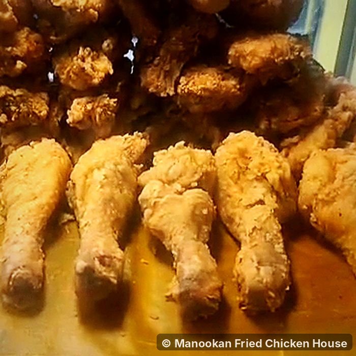 Golden fried chicken drumsticks with a craggy, crispy coating on a tray