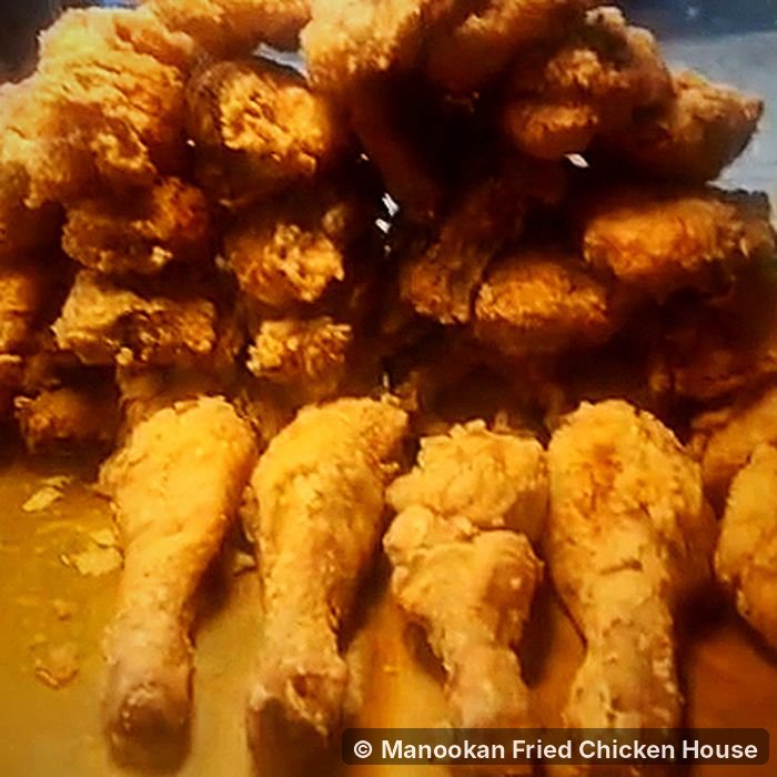 Fried chicken drumsticks and pieces on a tray at Manookan Fried Chicken House
