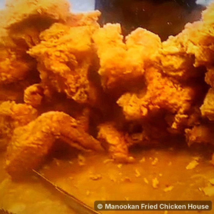 Golden fried chicken wings and pieces piled on a tray at Manookan Fried Chicken House
